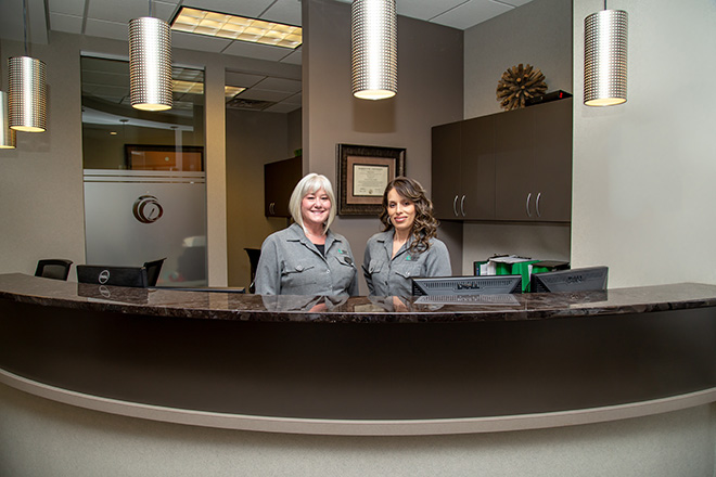 A woman and a man are standing behind a curved counter in an office with modern decor.