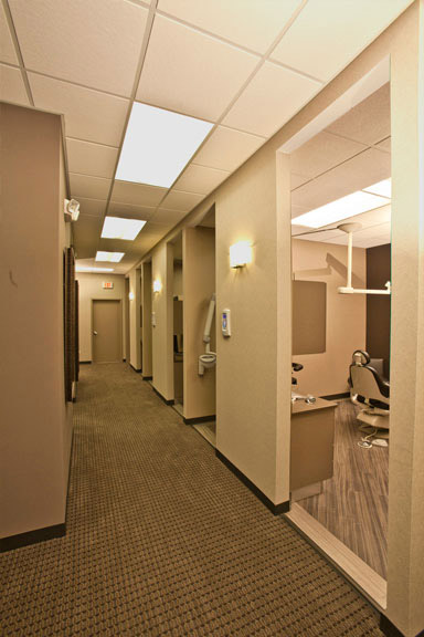 The image depicts an interior hallway of a medical or dental office, with a carpeted floor and walls, and is taken from the perspective of someone standing at the end of the corridor.