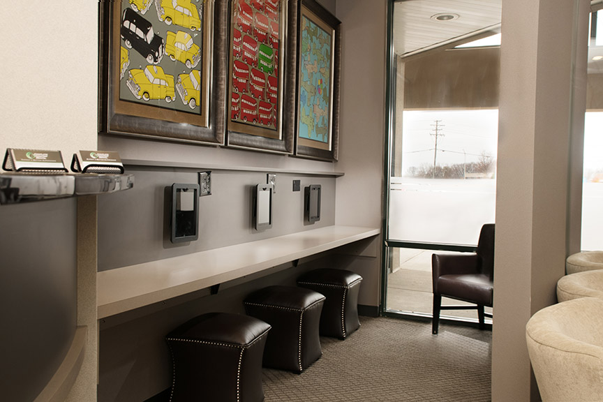 A modern lobby with a curved bench, stools, and a wall-mounted display of framed pictures.
