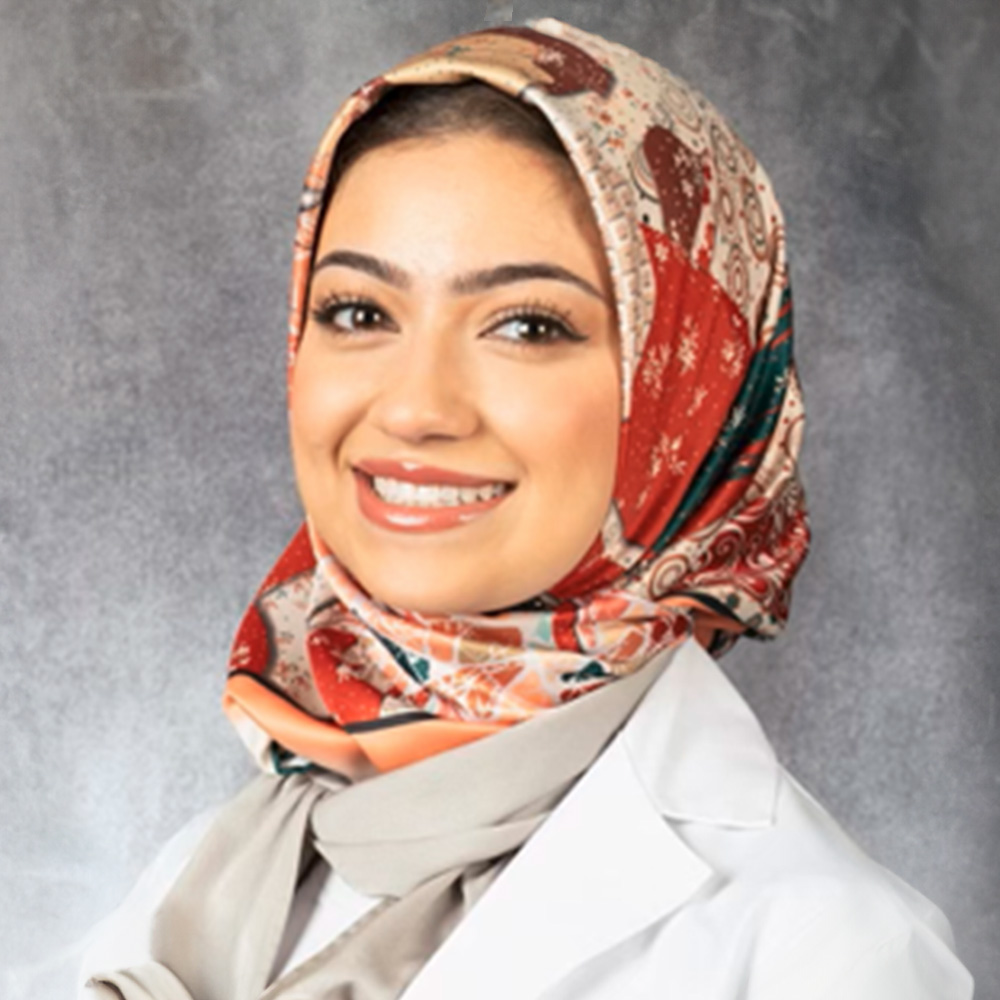 A young woman wearing a hijab, smiling, and posing for the photo.