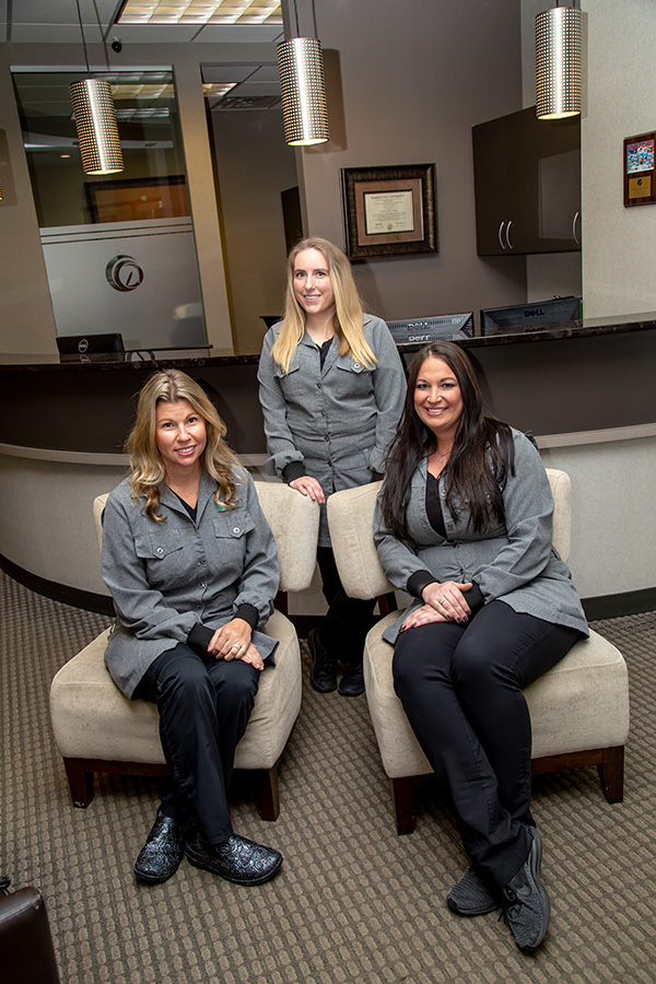 Three individuals in a professional setting, posing for the camera with smiles.