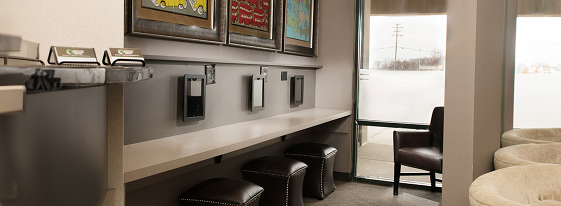 An office space with a desk and chairs, featuring framed artwork on the wall.