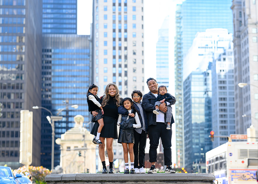 A family of five posing in front of a city skyline.