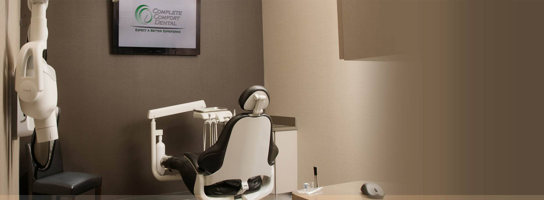 The image shows a dental office interior with a dental chair, a desk with a computer monitor and keyboard, and a sign on the wall.